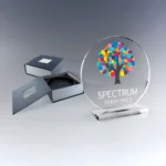 Trophée en verre personnalisé avec marquage couleur pour organisation ou événement Trophée en verre rond avec un logo en marquage couleur représentant un arbre et un texte personnalisé.