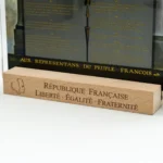 Gros plan sur le socle en bois gravé avec la devise républicaine Liberté, Égalité, Fraternité.